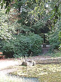 Etwas erhht hinter dem Teich stehend das Grabkeuz von Ludwig Friedrich von Mnchhausen